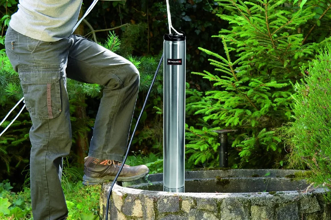 Person lässt Pumpe in Brunnen hinab